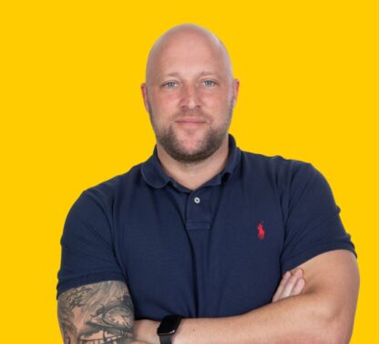 Pictured Adam Collier Head of Sales and a member of the Senior Leadership Team standing looking straight to camera with his arms folded.