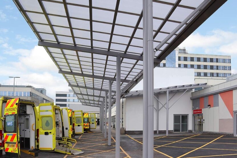 Picture shows a row of ambulances with their back doors open under the canopy