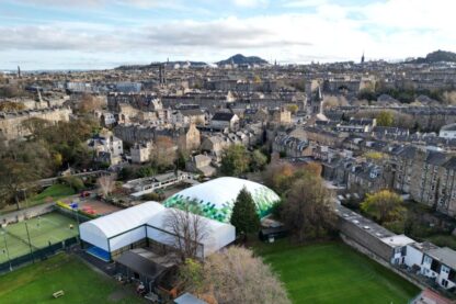 Picture show padel court shot from the side and showing the location including a field using a drone.