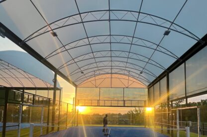 Picture show padel court and it's new canopy at East Grinstead Padel Club with the sun shining through at sunset.