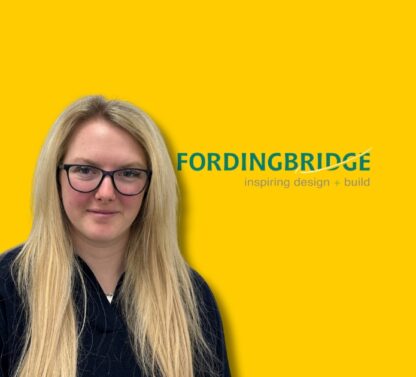 Picture shows Olivia LeGon standing in front of a yellow wall with the fordinbridge logo to her right