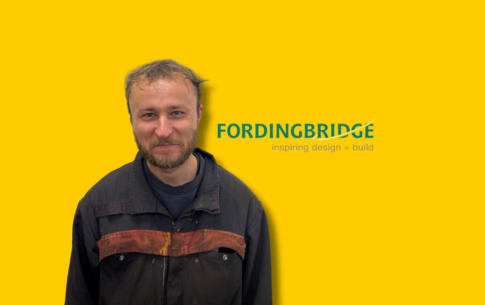 Picture show Harry the new Welder at Fordingbridge just smiling and standing in front of a yellow background.