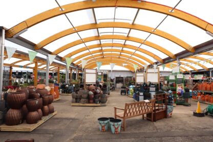 Interior view of barrel-vaulted hybrid canopy with timber arches at Glendoick Garden Centre plant display area