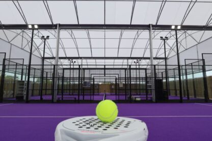 Purple covered padel courts at New Croft Sports Hub beneath a triple span all-weather canopy with a padel racket and ball in the foreground.