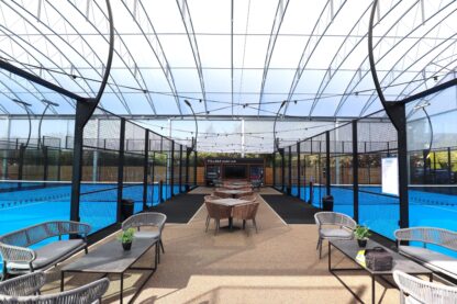 Premium covered padel courts at Village Health & Wellness Club featuring social seating areas beneath a large clear span all-weather canopy.